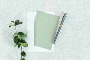 Business concept. Paper rustic sheet, envelope and pen on green background. photo