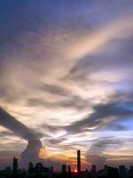 Vertical image, Sunset in the evening with dramatic shape and color of clouds and sky with Silhouette of cityscape, building skyline, nature background photo