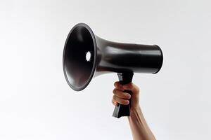 The hand holds a black megaphone on white background. Announcement concept. Shout It Out. photo