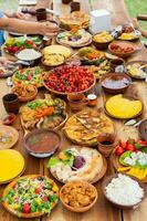 Homemade Romanian Food with grilled meat, polenta and vegetables Platter on camping. Romantic traditional moldavian food outside on the wood table. photo