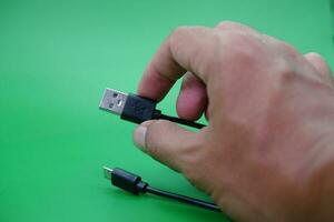 hand holding USB type A to USB micro B cable isolated on green background. photo