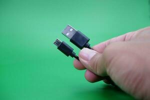 hand holding USB type A to USB micro B cable isolated on green background. photo