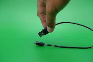 hand holding USB type A to USB micro B cable isolated on green background. photo