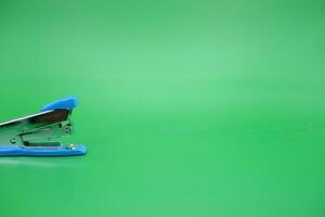 stapler isolated green background. Side view of a mini stapler. photo