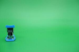 stapler isolated green background. Front view of the mini stapler. photo