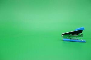 stapler isolated green background. Side view of a mini stapler. photo