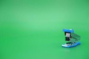 stapler isolated green background. Front view of the mini stapler. photo