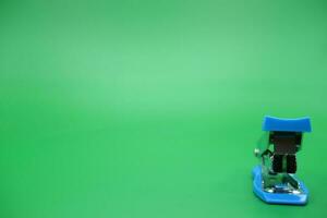 stapler isolated green background. Front view of the mini stapler. photo