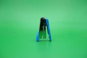 stapler isolated green background. mini stapler upside down. photo