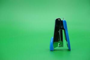 stapler isolated green background. mini stapler upside down. photo