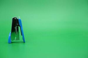 stapler isolated green background. mini stapler upside down. photo