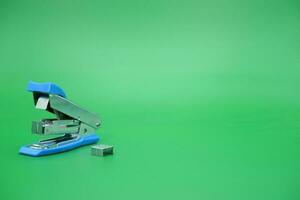 stapler isolated green background. Side view of a mini stapler. photo