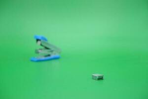 stapler refill and blurred stapler isolated green background. photo