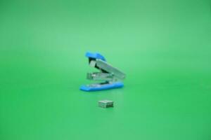 stapler refill and blurred stapler isolated green background. photo