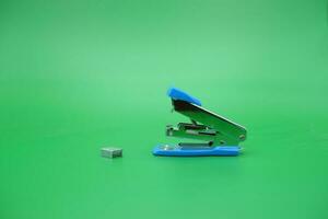 stapler isolated green background. Side view of a mini stapler. photo