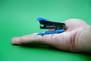 hand holding stapler isolated on green background. photo