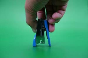 hand holding stapler isolated on green background. photo