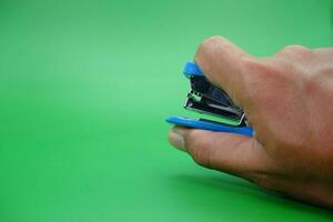 hand holding stapler isolated on green background. photo