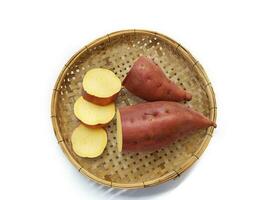 Sweet potato in woven wooden tray isolated on white background. Top view. photo