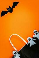 Halloween sale banner with bat, ghost and bag on orange background. photo