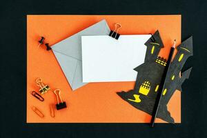 Halloween office desk, card, envelope, pencil and office supplies on black table. photo