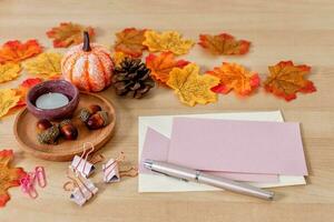 Frame made of craft paper envelope, blank card, leaves, rope on wooden background. photo