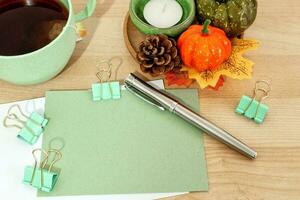 Autumn or winter season cozy composition with greeting card, tea cup, pen, on desk table. photo