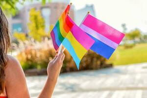 Gender queer. Female hand hold lgbtq, bisexual and pan sexual flag. Selective focus. photo