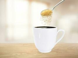 Spoon pour sugar into a coffee mug on the wooden floor inside the room. photo