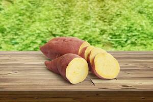 sweet potato on wooden table There is a garden field in the background. photo