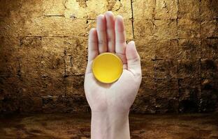 Gold coin in hand with gold leaf background photo