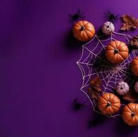 Halloween square card. Pumpkins, cobweb with spiders, dry leaves on purple background. Top view. photo