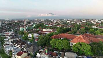 aéreo Visão do habitação dentro yogyakarta cidade às pôr do sol com Visão do montar merapi dentro a distância, Indonésia. video