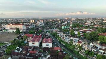 Aerial view of housing in Yogyakarta city at sunset with view of Mount Merapi in the distance, Indonesia. video