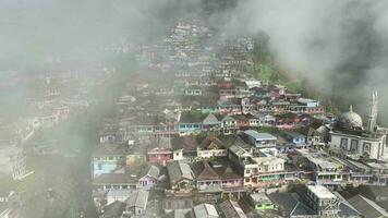 aéreo Visão do lindo colorida aldeias dentro Nepal furgão Java em montar somando, magolang, central Java, Indonésia. escondido Vila atrás nuvens e névoa em a declives do montar somando. video