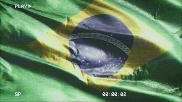 VHS video casette record Brazil flag waving on the wind. Glitch noise with time counter recording Brazilian banner swaying on the breeze. Seamless loop.