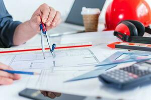 Hands of architect or engineer using pencil working with blueprint on desk in office. photo