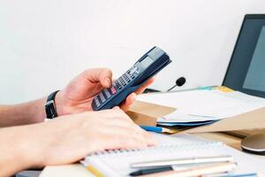 Businessman doing accounting and calculating with a calculator in a desktop at office. Side view. photo