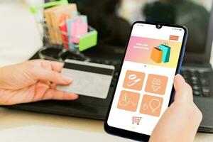 close up of female hand holding a smart phone with shopping app, front view, on desk. photo