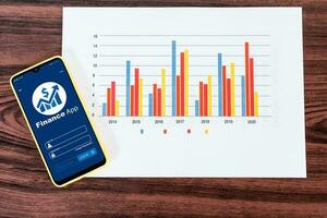 Mobile phone with financial application, with statistical graphs on desktop. photo