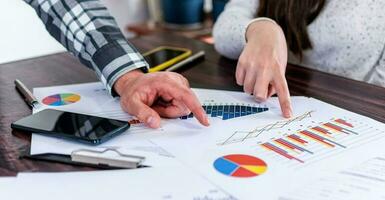 Two businesspeople analyzing graphs, without faces, analyzing data with investor at home office. Selective focus. photo