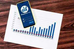 Mobile phone with financial application, with statistical graphs on desktop. photo