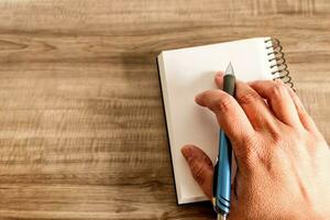 Female hand with notebook on wooden desk. Business, education and people concept. photo