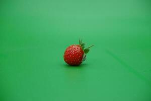 a red strawberry isolated on a green background. photo