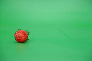 un rojo fresa aislado en un verde antecedentes. mordido fresas foto