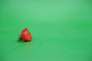 a red strawberry isolated on a green background. bitten strawberries. photo