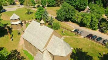 Aerial view Young lithuanians relax on sunday mass by St. Joseph Church in Paluse, Lithuania. Stave Churches in Europe. Old heritage sites. Walls formed by vertical wooden boards. video