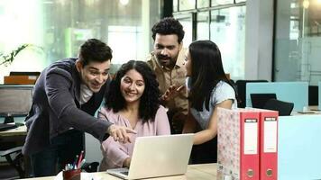 Video of colleagues looking at laptop screen while discussing project at office