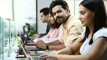 Video of confident team working together sitting in row next to each other in office.