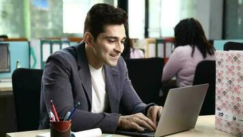 Video Young man Showing Thumbs up Hand Sign  Sitting at his Workplace and Smiling at the Camera